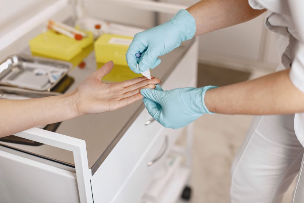 Close-up of a healthcare worker using gloves to apply a bandage on a patient’s finger in a medical setting