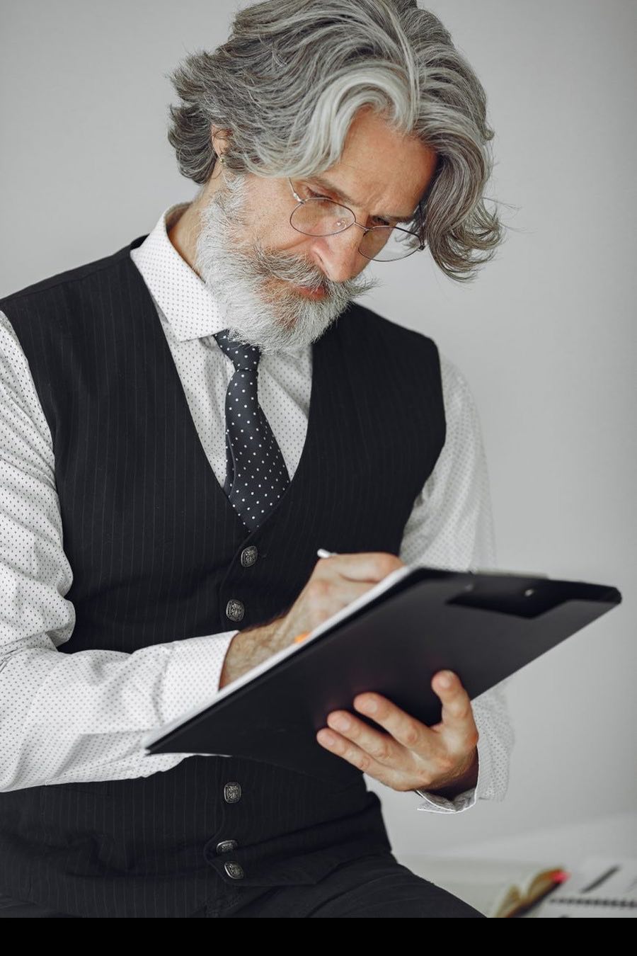A silver-haired senior practitioner working through a document, pen in hand