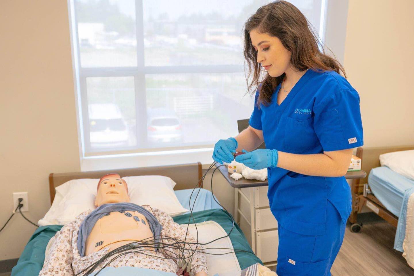 A clinician in scrubs working through a procedure in a clinical simulation suite