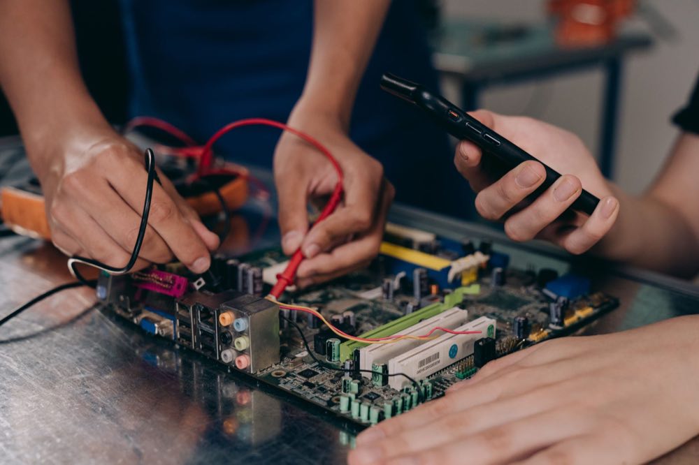 Engineers examining a circuit board with test equipment