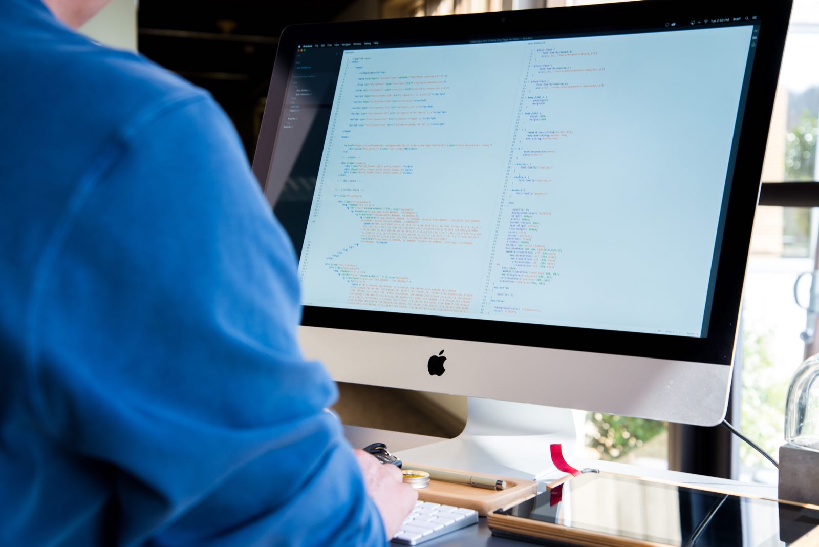 A software developer writing code on a large monitor in a modern office