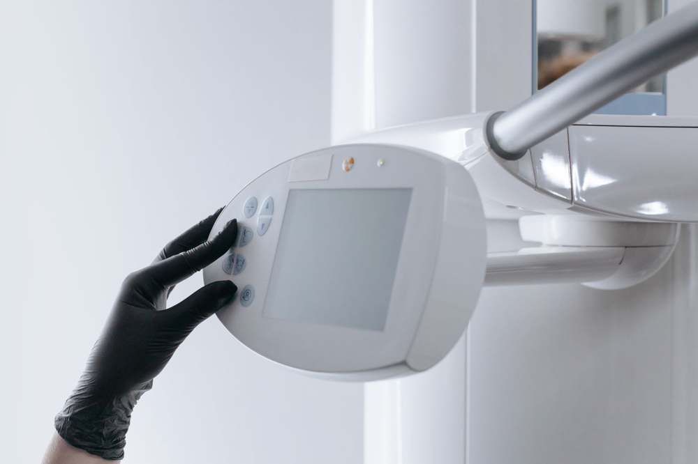 A gloved hand operating an imaging system control panel