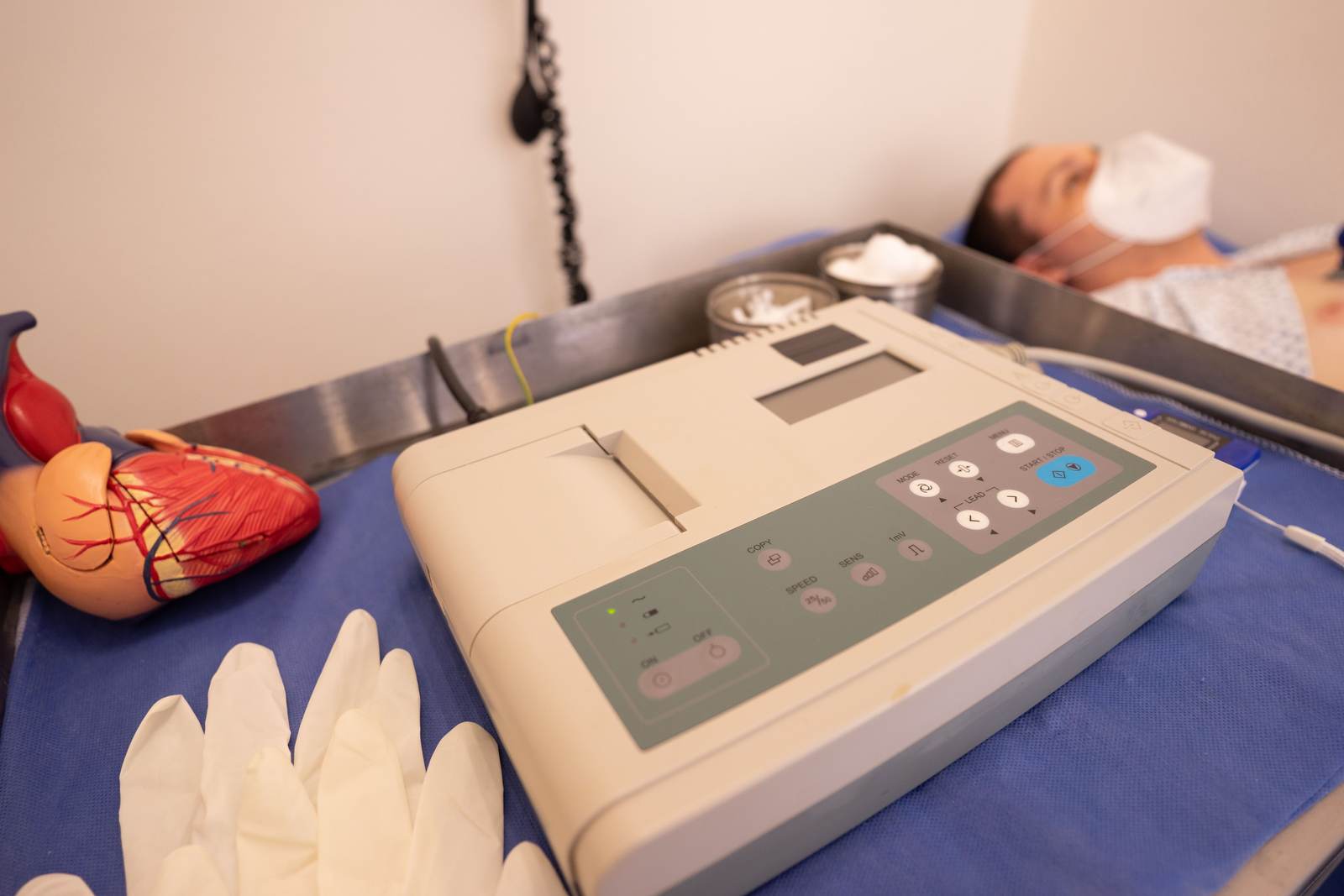 An ECG machine beside a model heart in a hospital setting