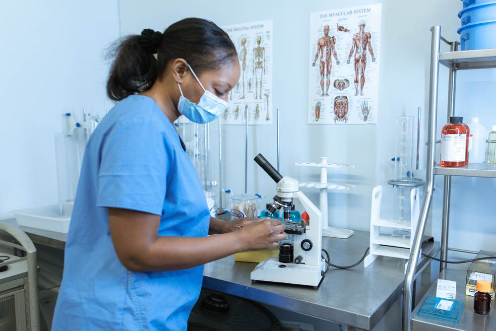 A healthcare worker using a microscope in a laboratory
