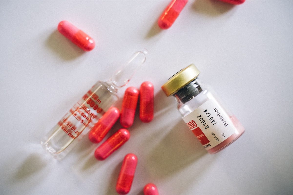 A medication vial, bottle, and capsules arranged on a bench