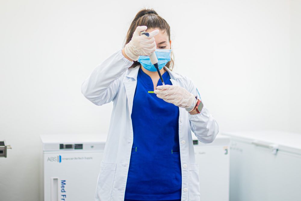 Scientist pipetting beside an ultra-low temperature freezer