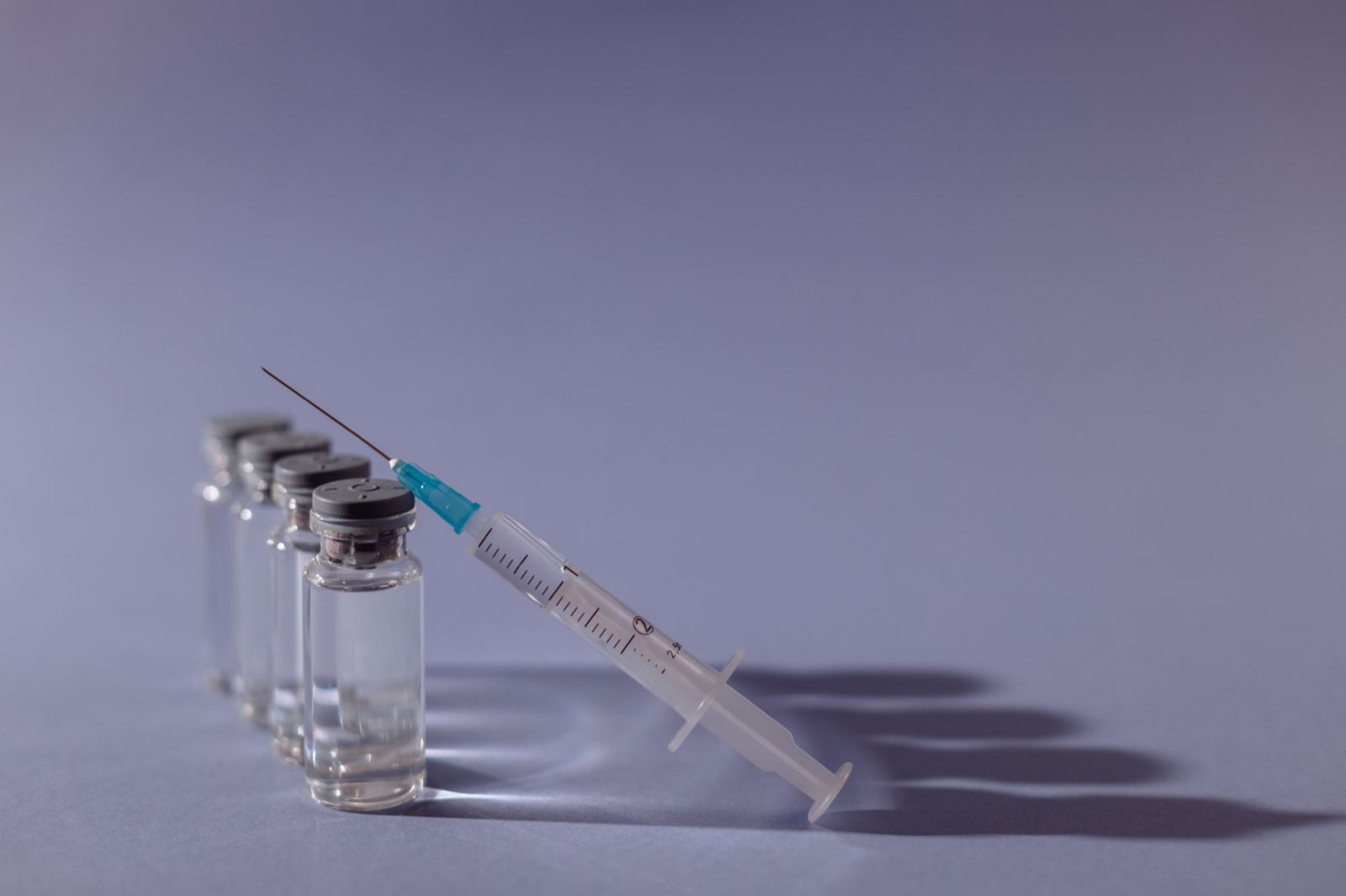Vaccine vials and a syringe in a clinical setting