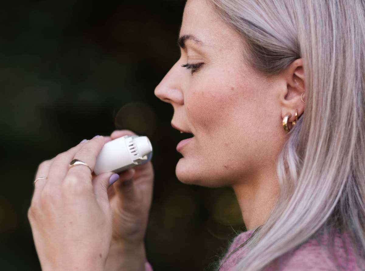 A woman using a personal inhaler
