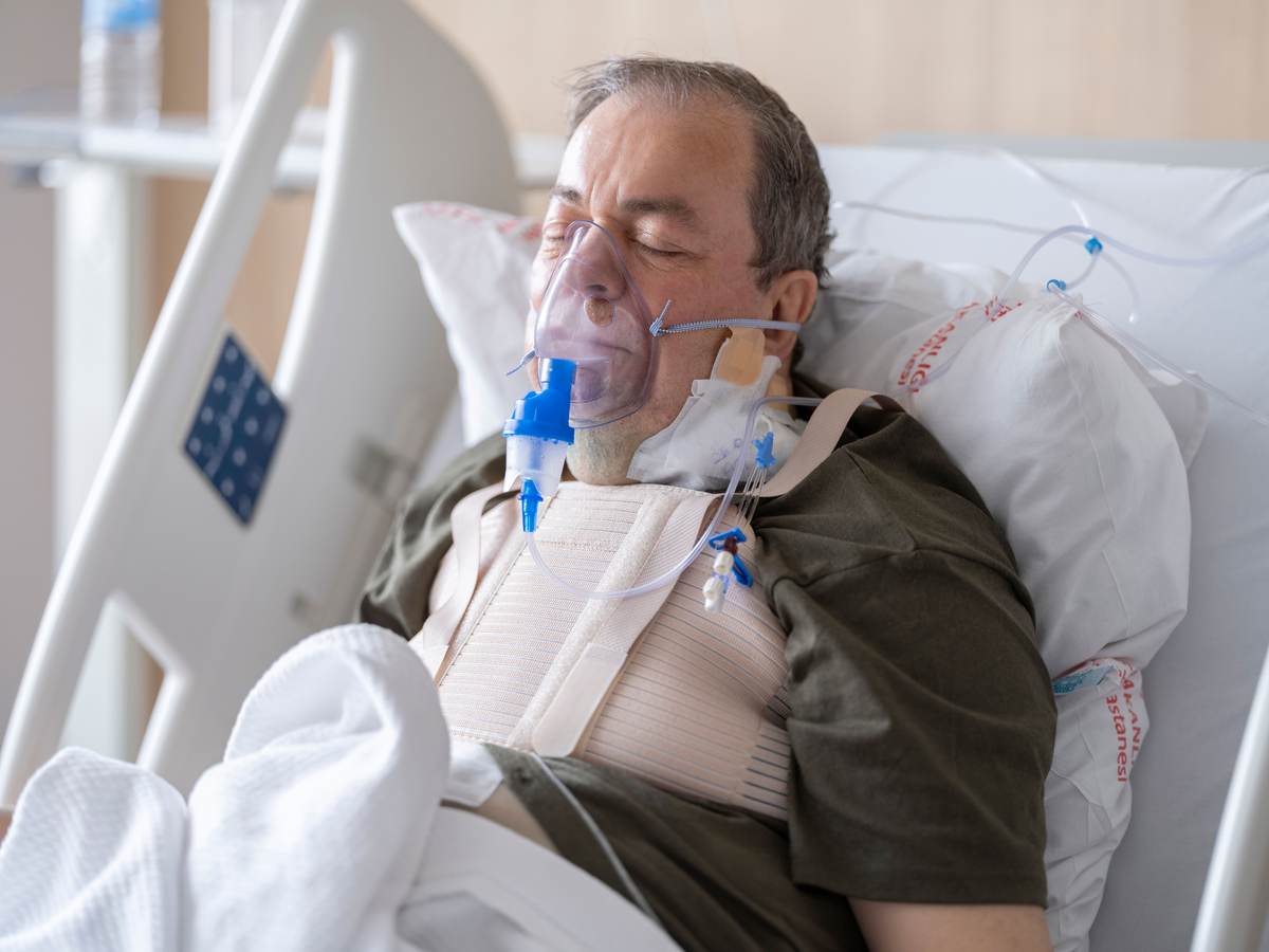 An elderly patient using an oxygen mask in a hospital bed