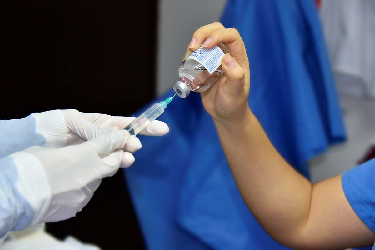 A healthcare worker drawing medication from a vial into a syringe
