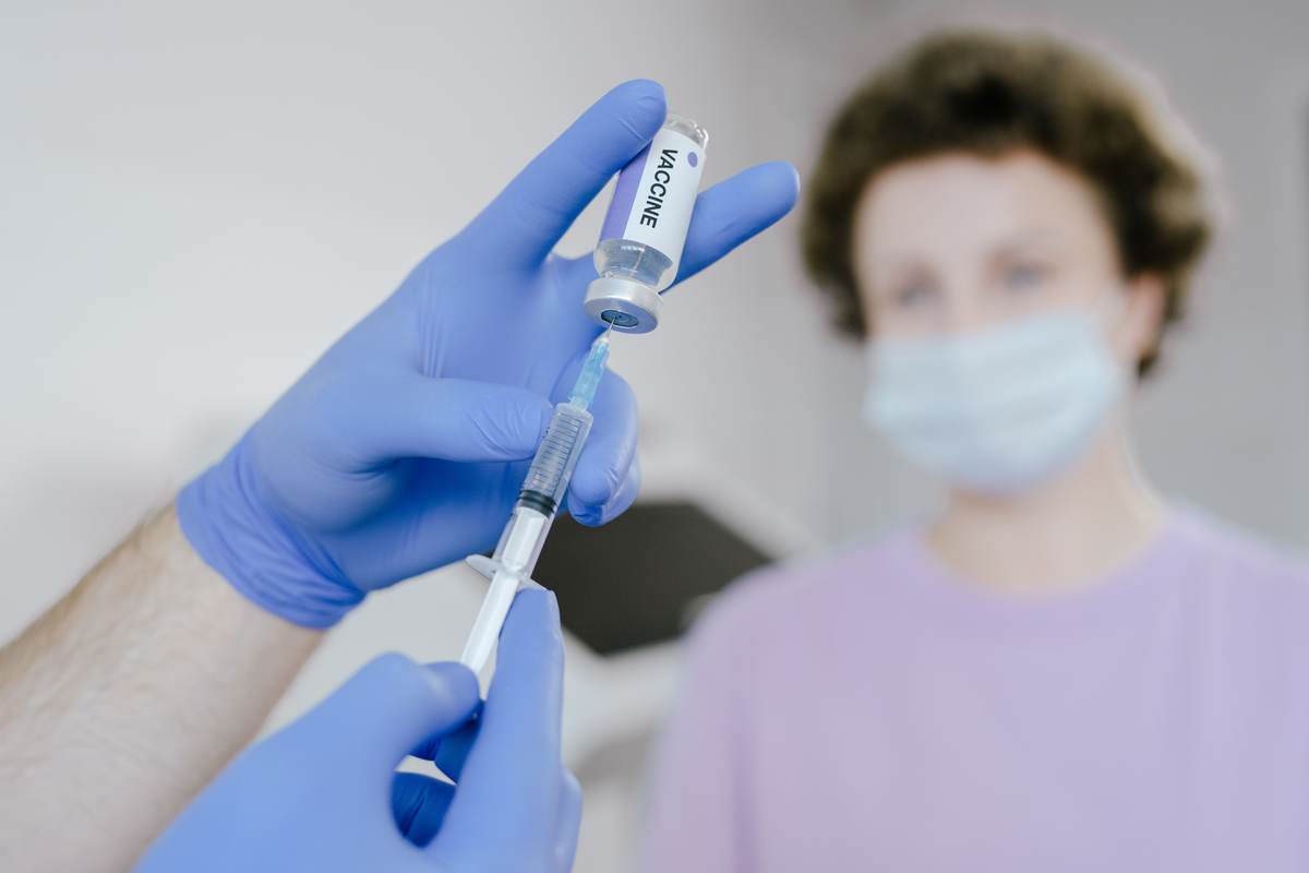 A healthcare professional in gloves filling a syringe