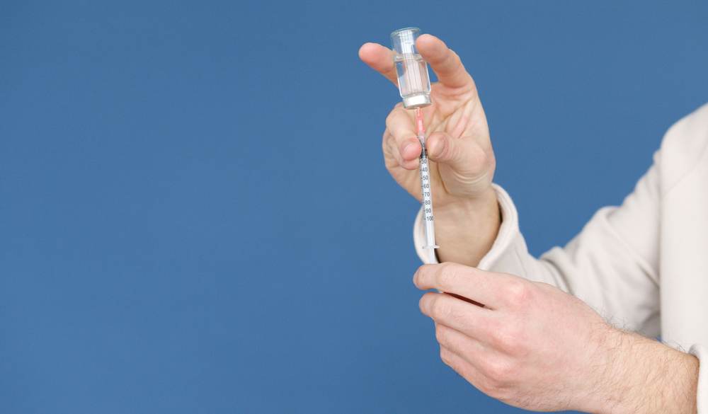 A doctor preparing an injection with a syringe and vial