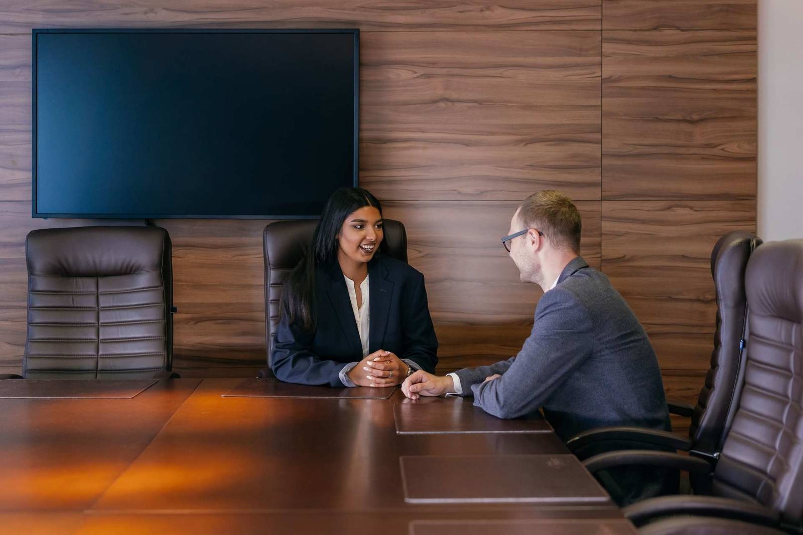 Two colleagues in a conference room discussing a technical document together