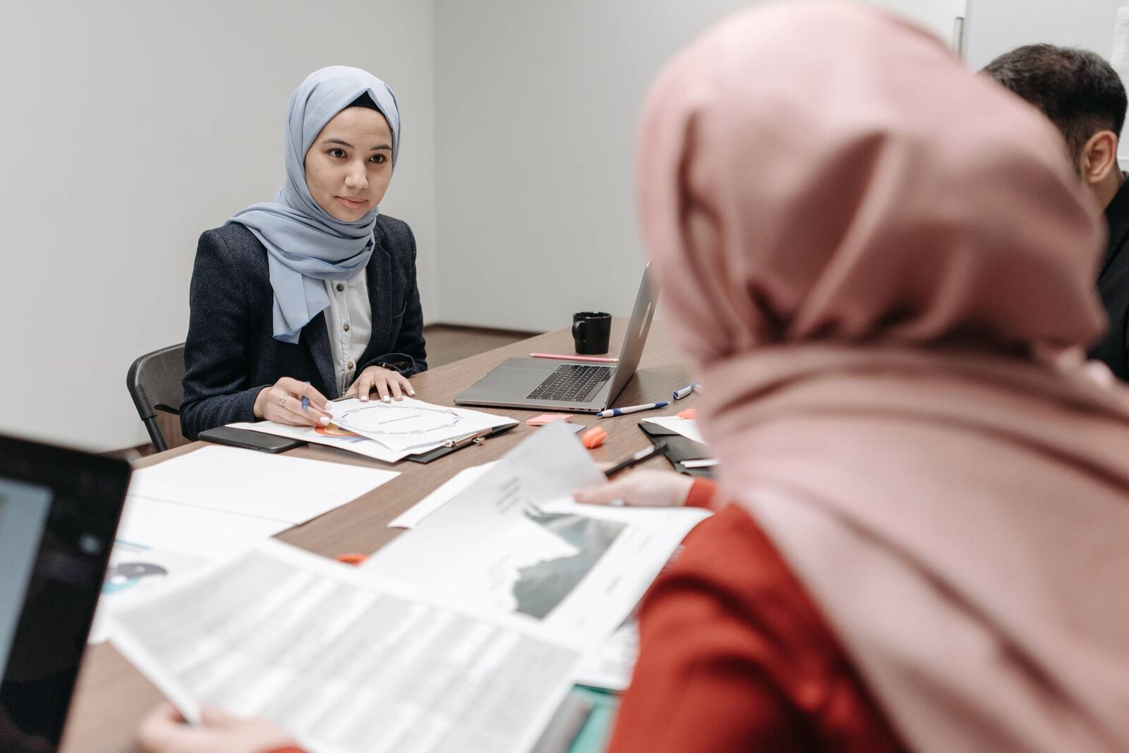A regulatory team reviewing multiple printed safety case reports spread across a conference table