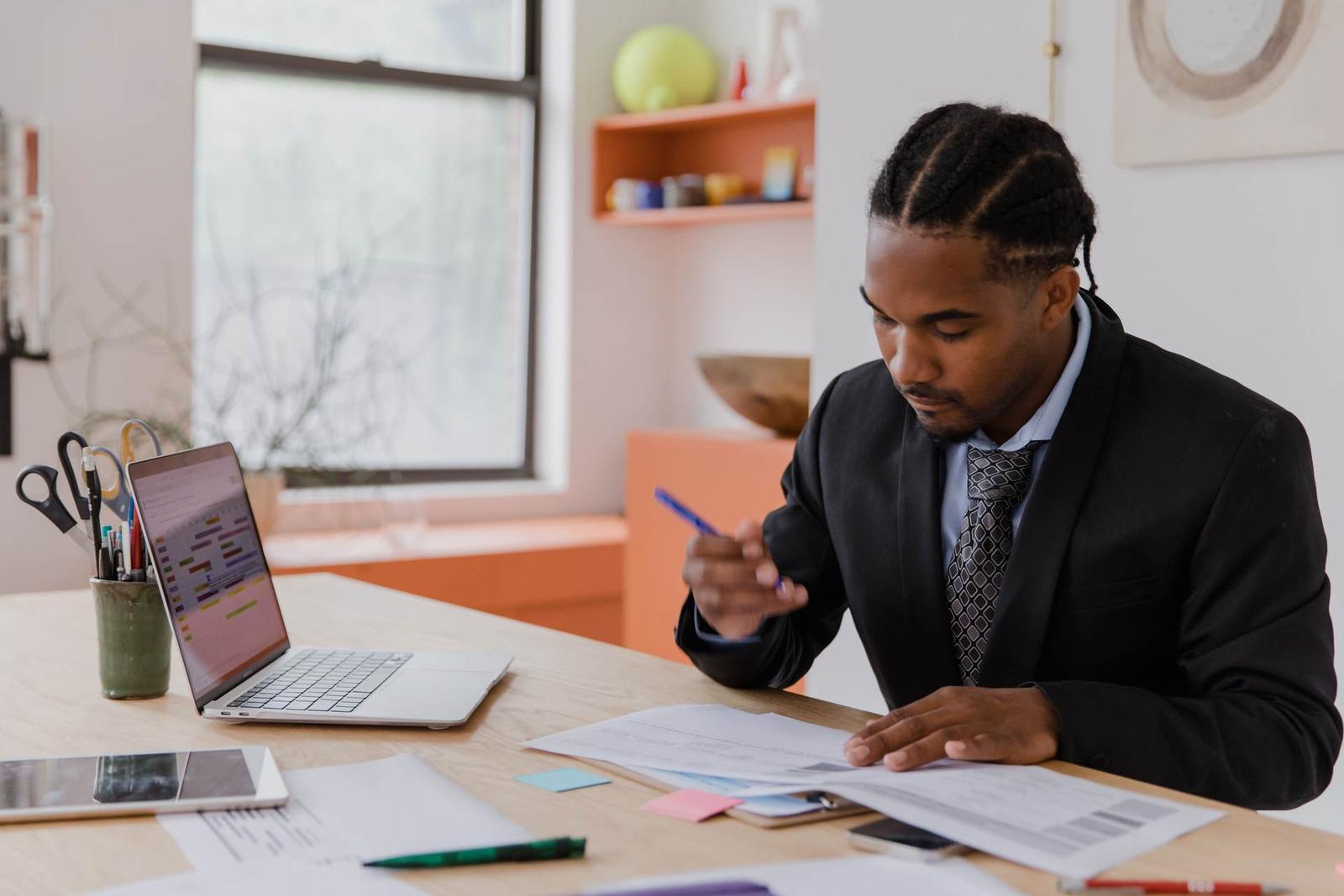 Regulatory professional in a dark suit reviewing printed compliance documents at a desk