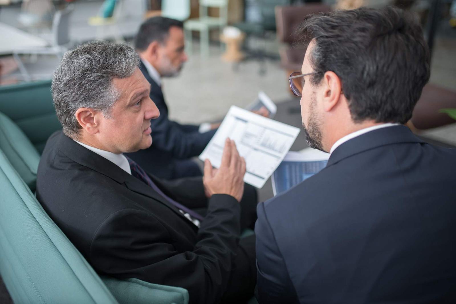 Two senior regulatory professionals reviewing a chart-filled document together in a bright office lounge