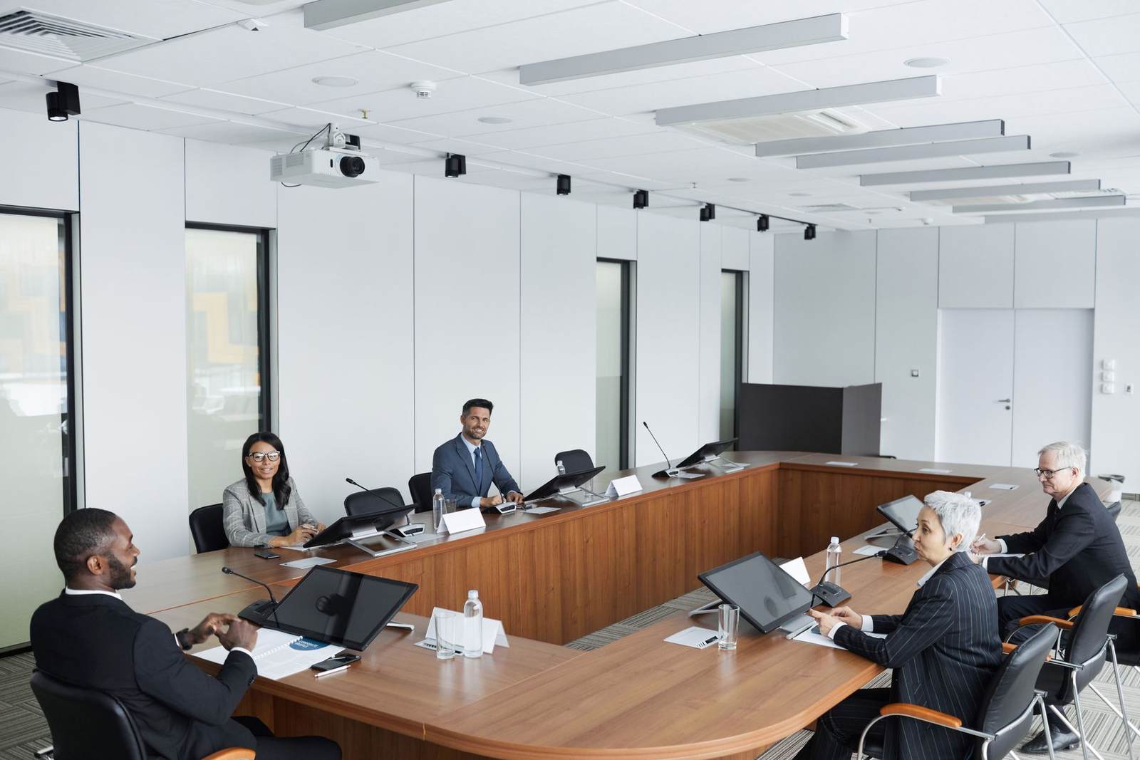 Executives seated at a U-shaped boardroom table for a formal review meeting
