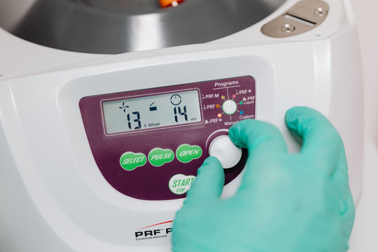 A gloved hand operating the control panel of a laboratory instrument