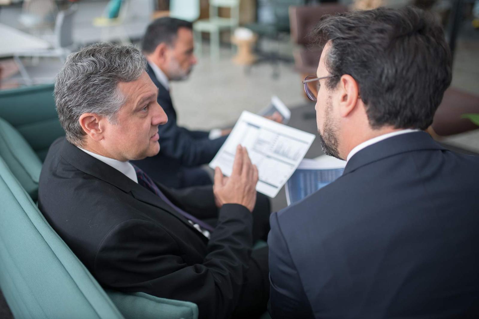 Two senior colleagues in suits reviewing a data report with a bar chart together