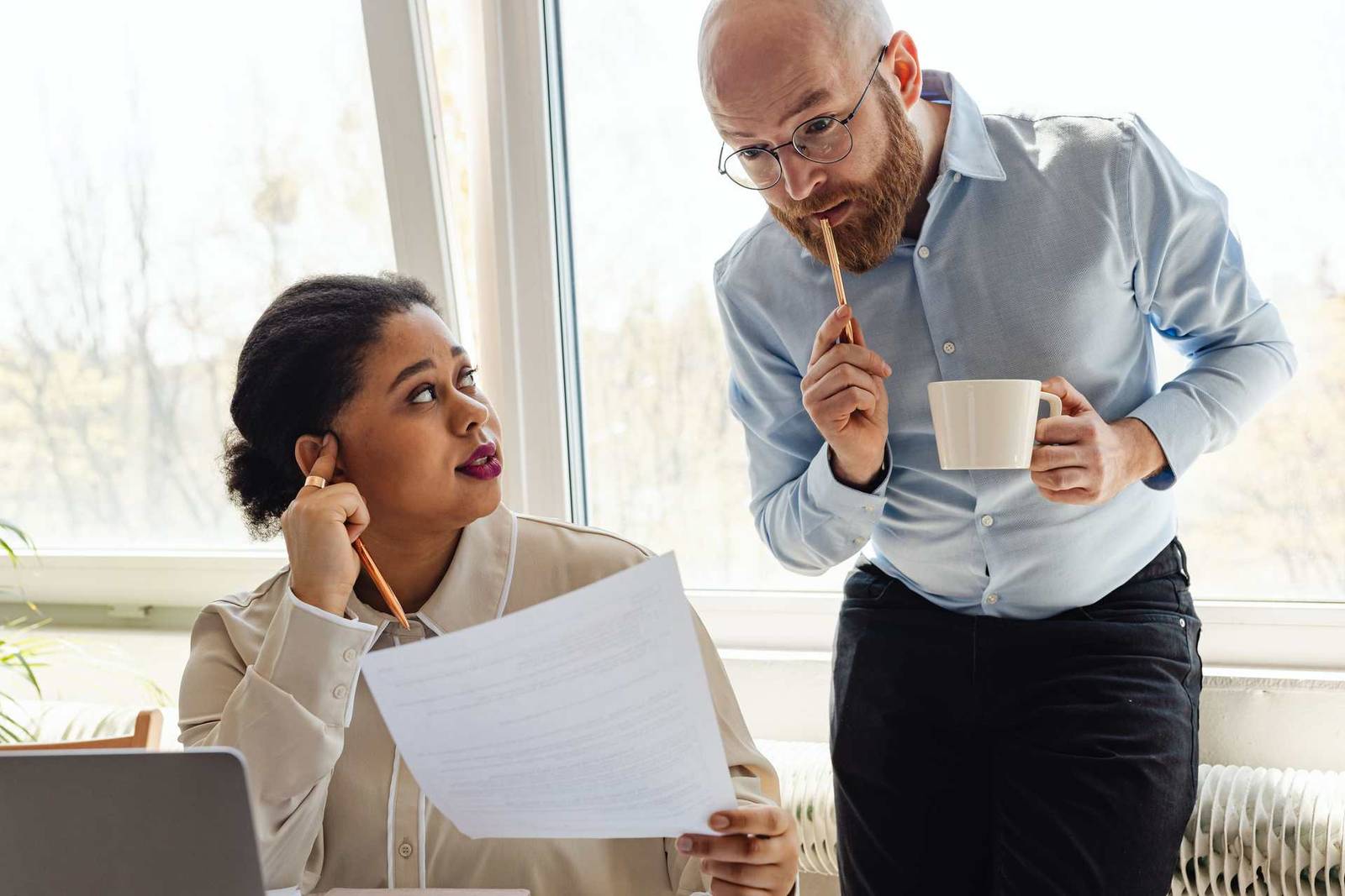 Two colleagues closely reviewing a printed document with skeptical expressions