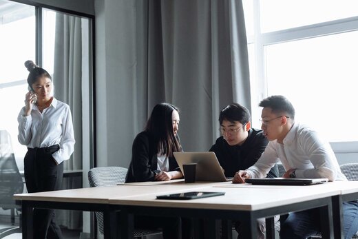 Four colleagues reviewing data together on a laptop at a conference table