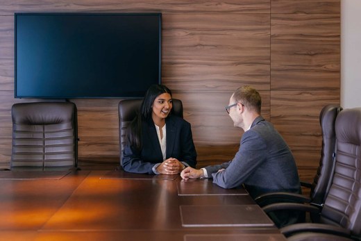 Two colleagues in a conference room discussing a technical document together