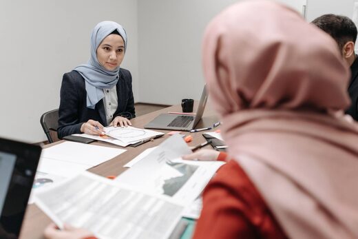 A regulatory team reviewing multiple printed safety case reports spread across a conference table