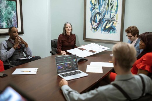 Senior consultant presenting pinned charts to colleagues around a boardroom table