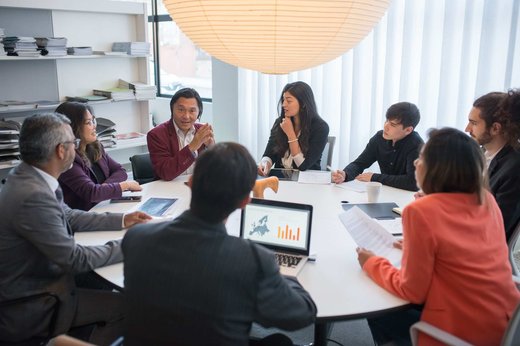 A diverse team of regulatory professionals in discussion around a conference table, with a laptop showing a Europe map and chart