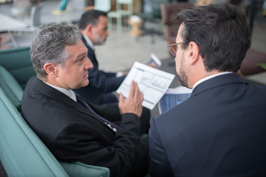 Two senior regulatory professionals reviewing a chart-filled document together in a bright office lounge