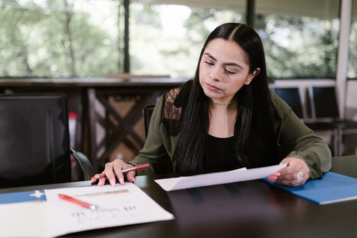 Woman in an office reviewing printed data pages and a folder of documents at a conference table