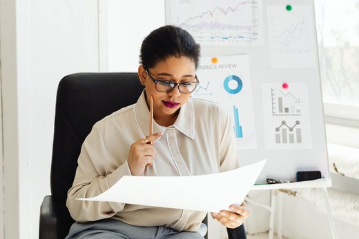 Analyst reviewing printed data charts against a review board in a bright office