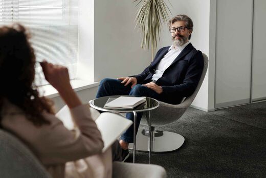 Senior consultant in a navy blazer speaking with a colleague in a bright white office