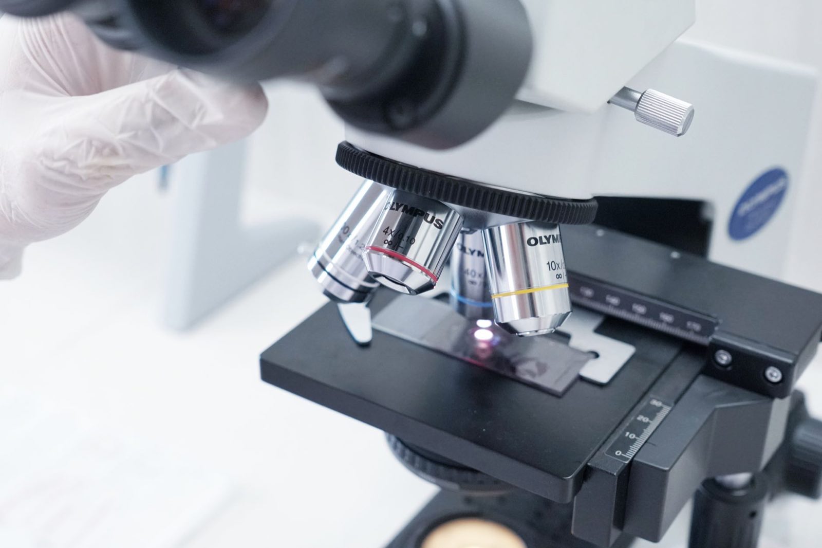 A scientist examining material samples under a laboratory microscope