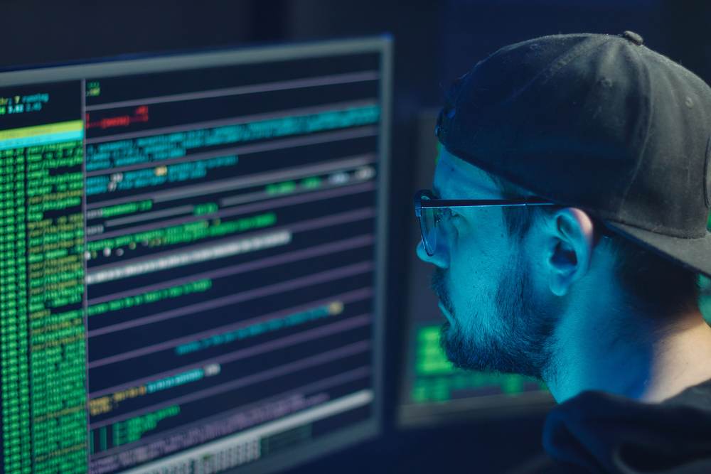 A security expert inspecting lines of code on multiple monitors