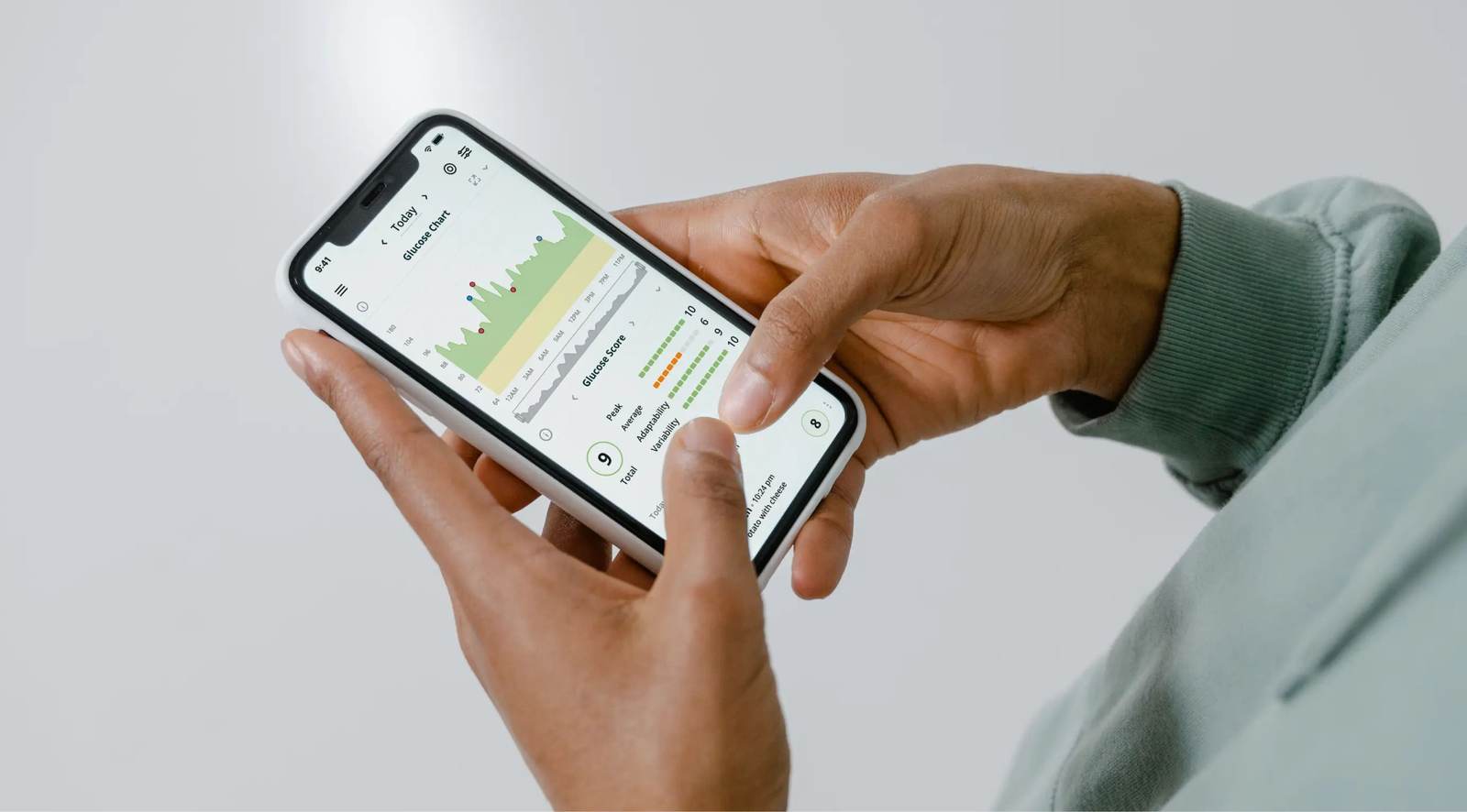 Hands holding a smartphone showing a health tracking app with charts and data