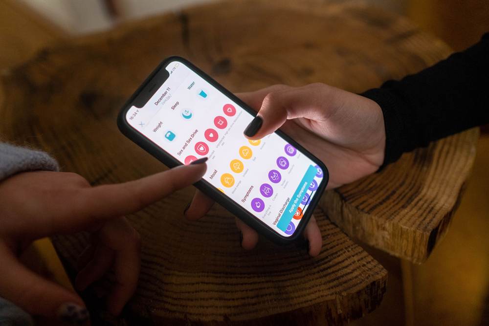 Close-up of hands using a health tracking app on a smartphone
