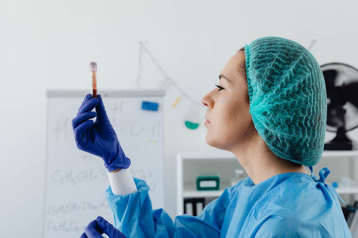 A scientist in protective gear inspecting a blood sample
