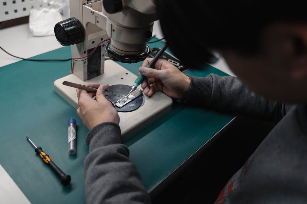 A technician using a microscope with precision measurement tools