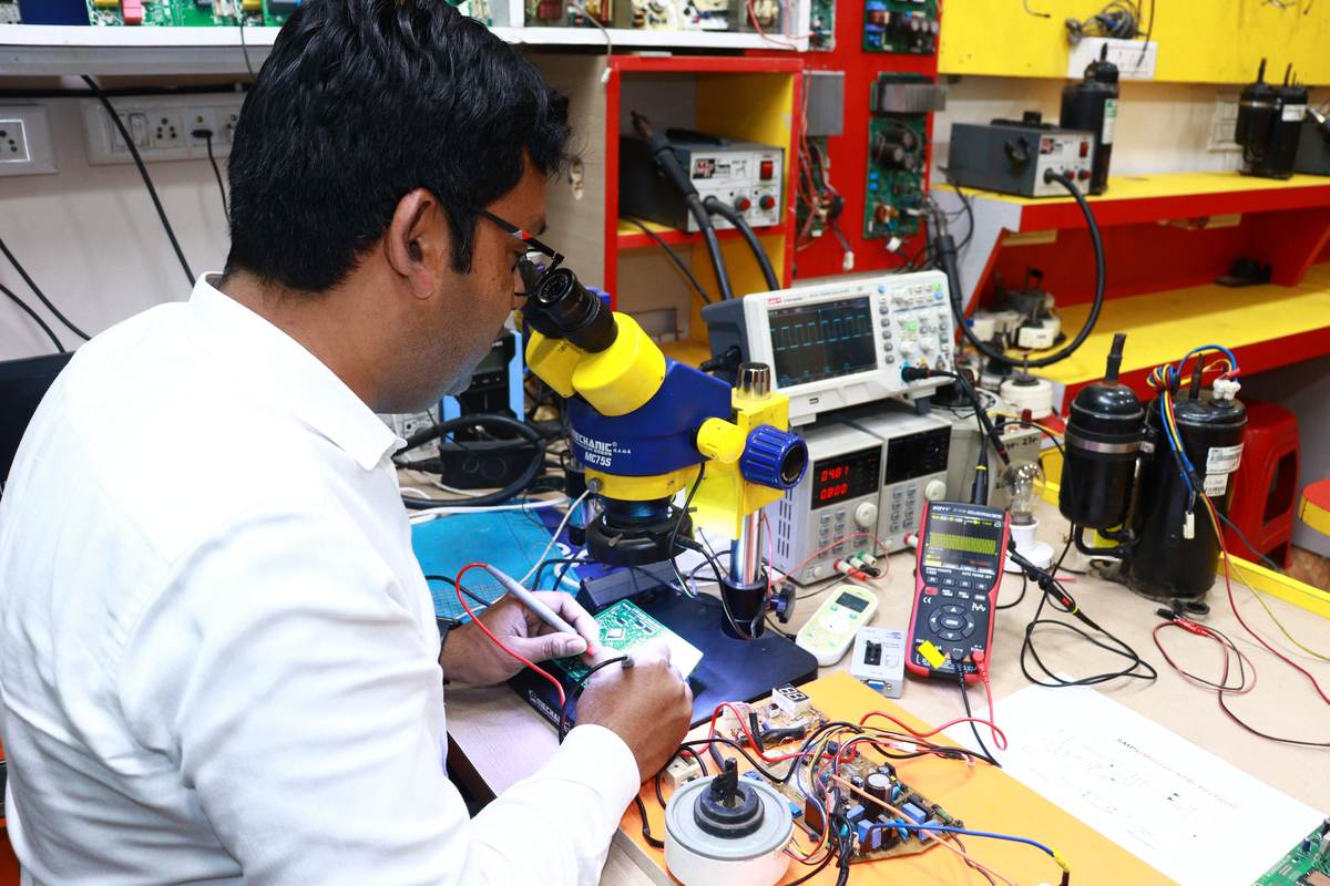 A technician working with precision instruments under a microscope in an electronics lab