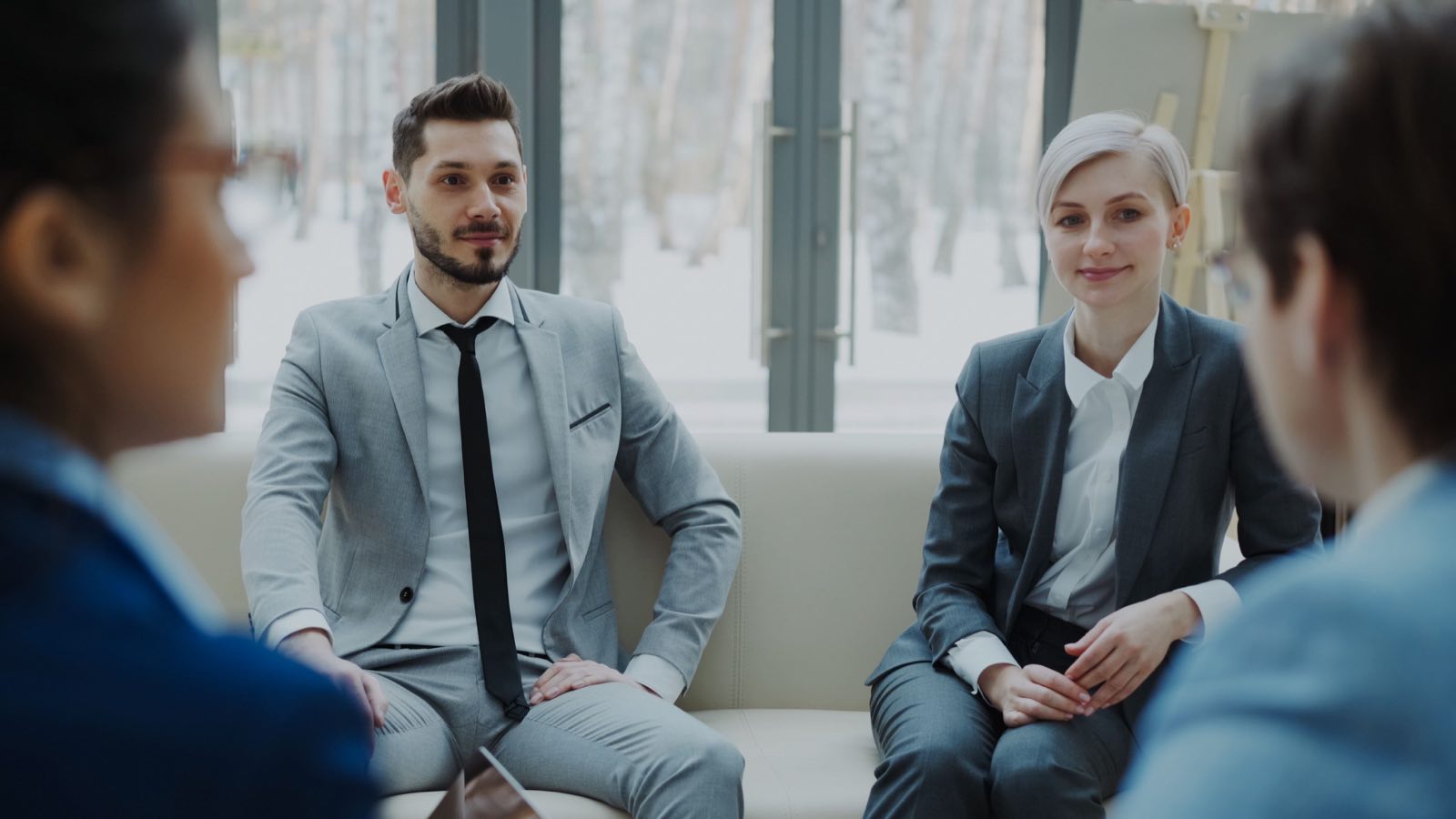 A leadership team in suits working through a decision in a bright conference room