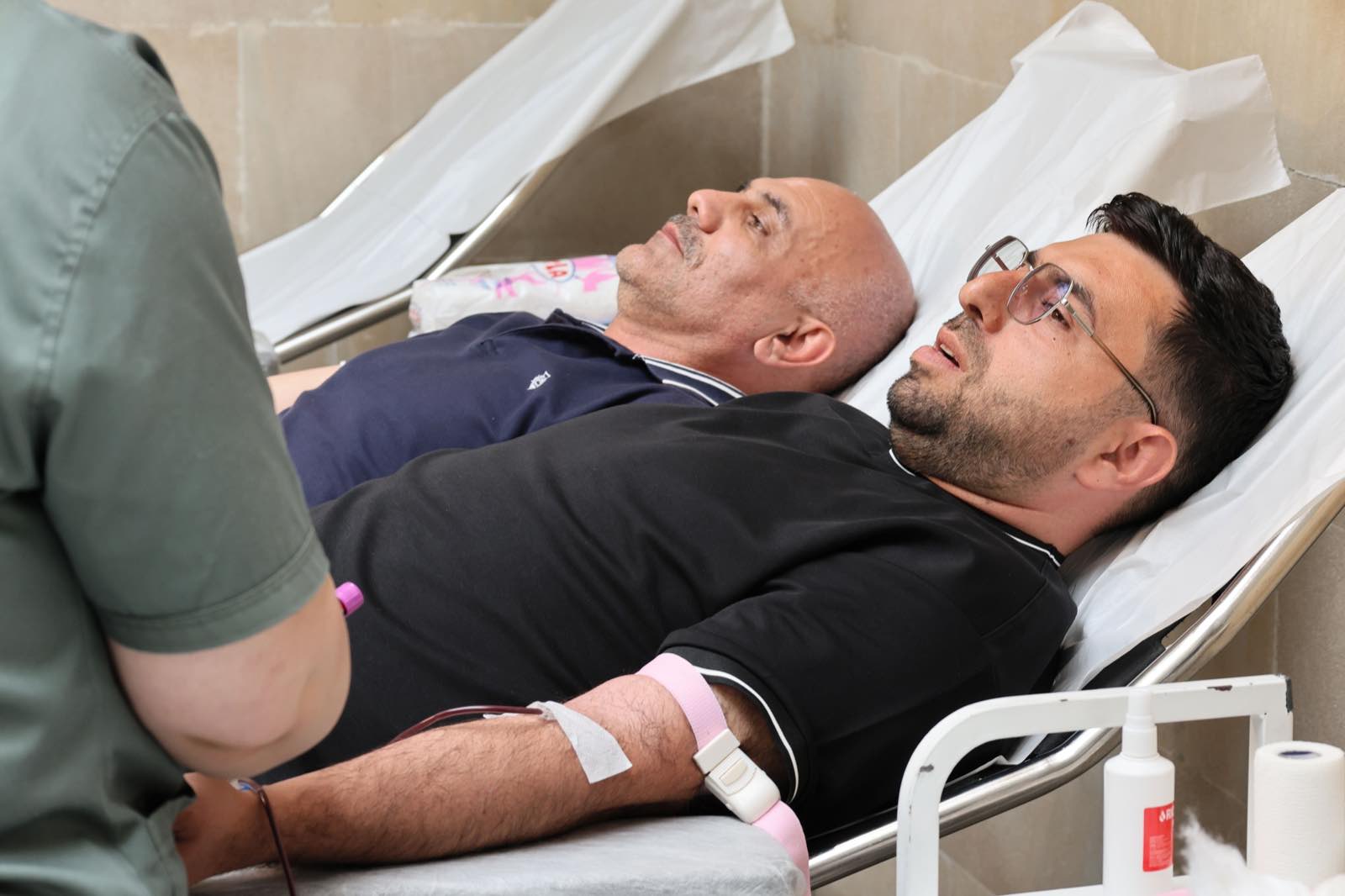 Two men are lying on medical beds while donating blood at a clinic