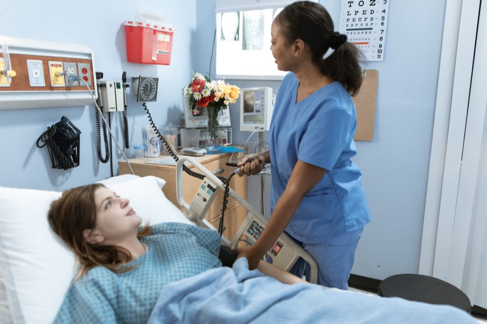 Nurse providing care to a patient in a hospital room with medical equipment