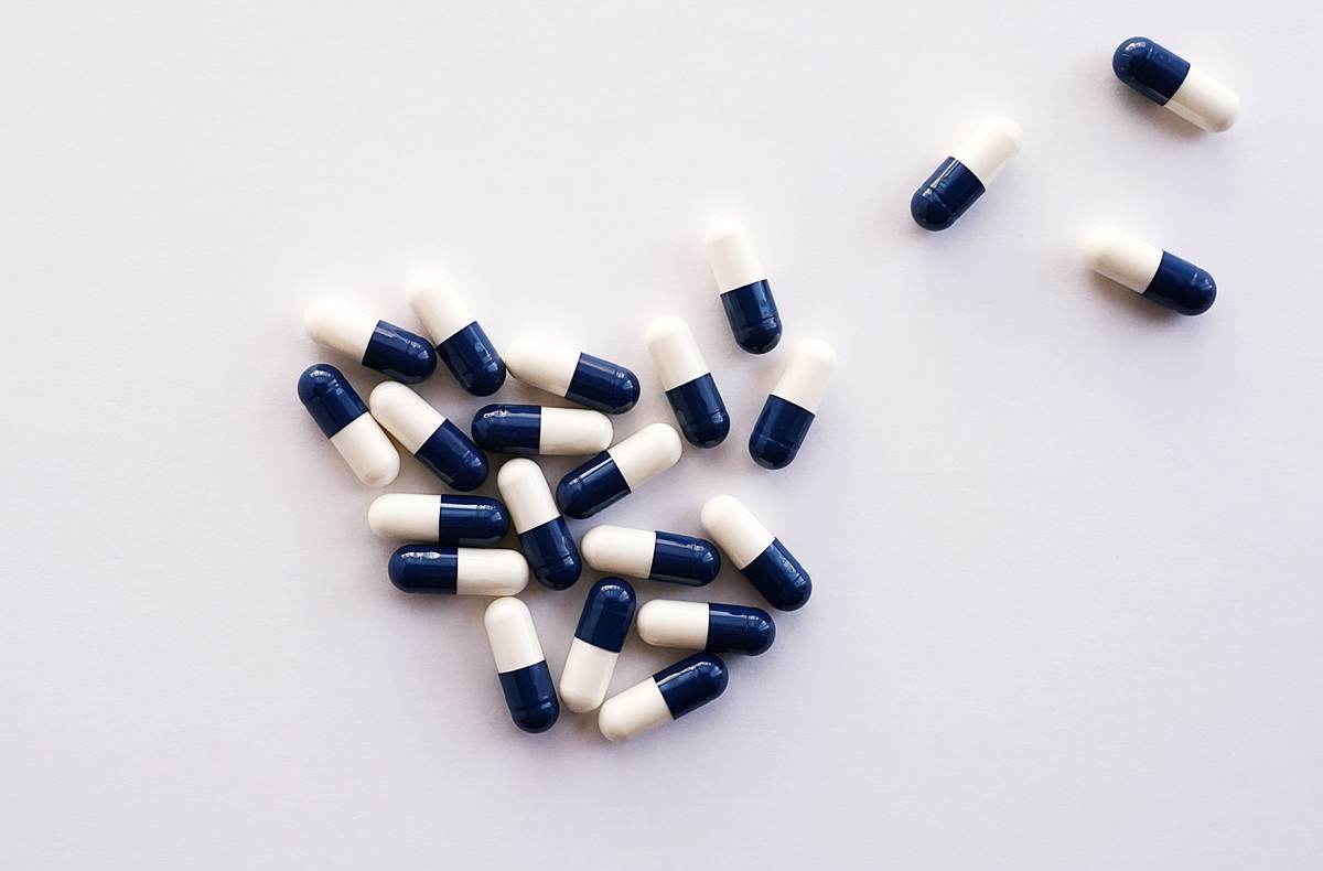 A flat lay of blue and white capsules on a white surface