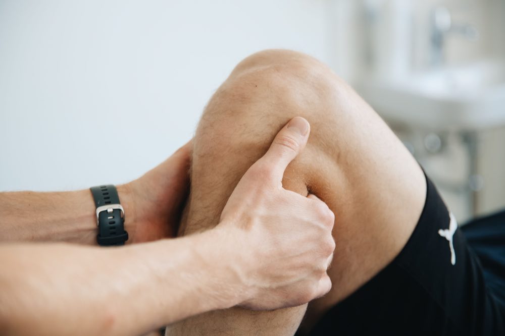 Close-up of a physiotherapist massaging a patient's knee during therapy