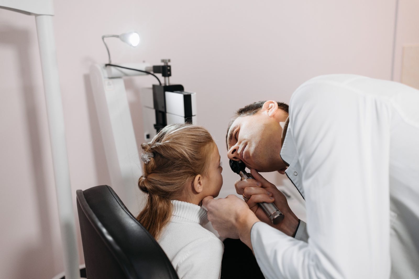 A doctor examines a young girl's ear during a medical appointment in a clinic