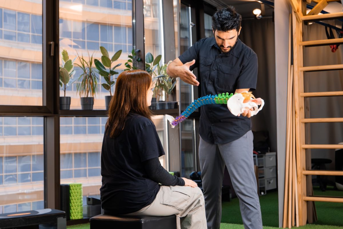 Chiropractor demonstrating spine anatomy to a patient during consultation indoors