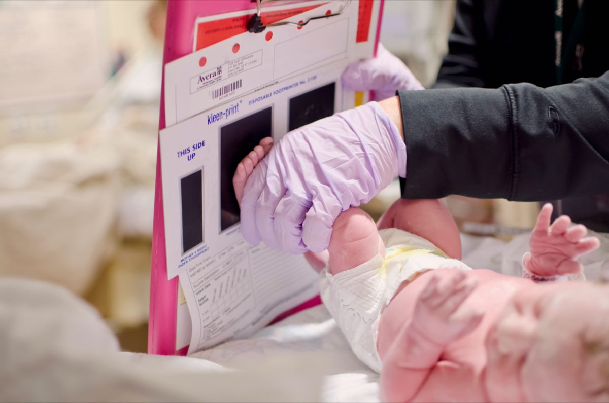 A newborn baby gets a footprint taken by a nurse in a hospital setting