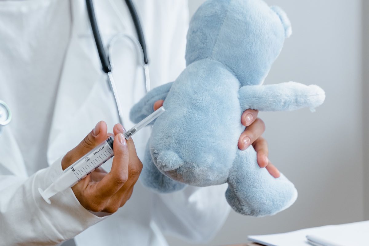 Close-up of a doctor using a syringe on a plush toy for educational purposes