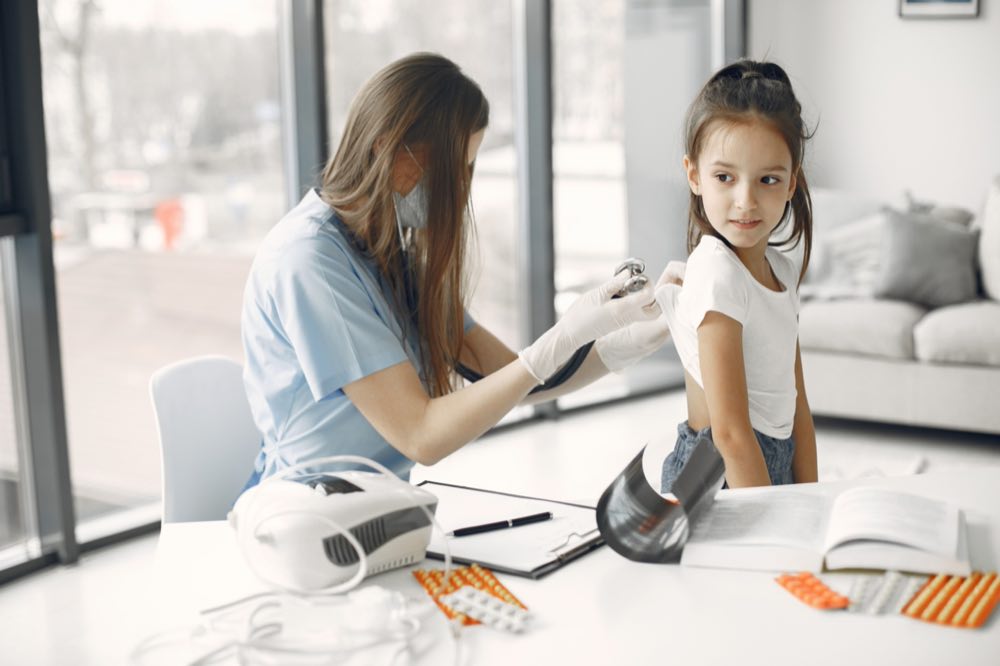 Young girl in clinic receiving a checkup from a female doctor with stethoscope